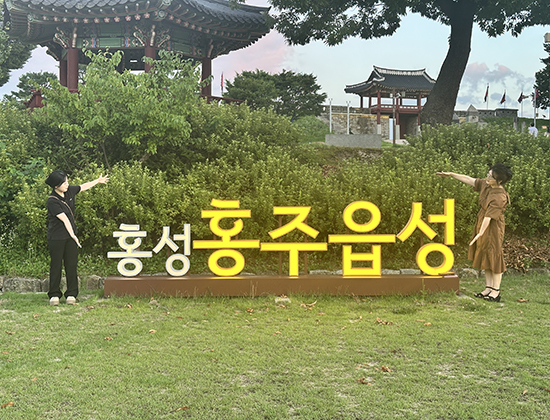 ‘홍성 홍주읍성’이라고 적힌 장식물 앞에서 포즈를 취하는 두 사람